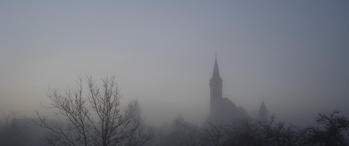 Kirche und Bäume im Nebel