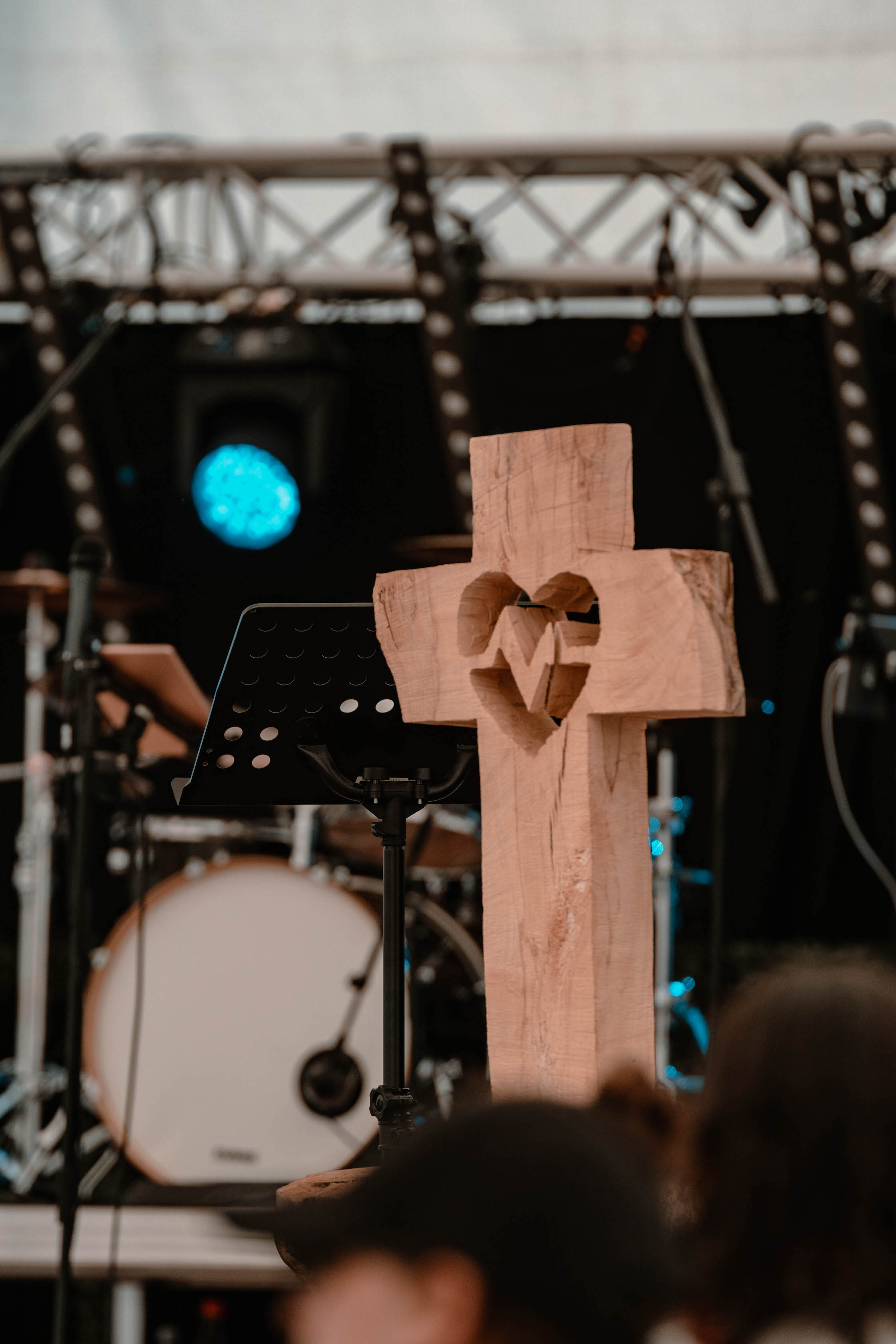 geschnitztes Holzkreuz mit geschnitztem Herz und Pulslinie auf der Bühne stehend