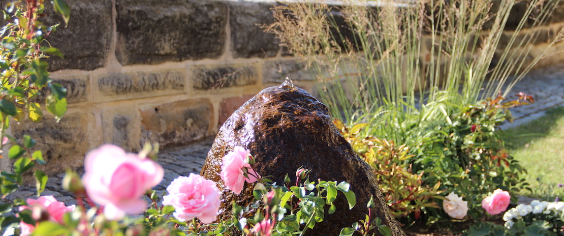 Steinbrunnen im Frühling/Sommer im Kirchgarten