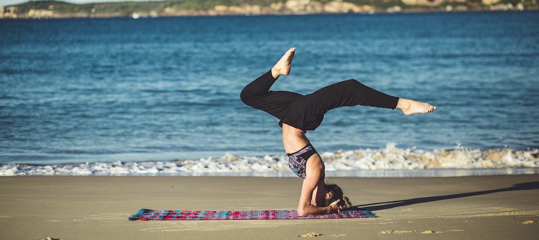 Frau macht Kopfstand am Strand