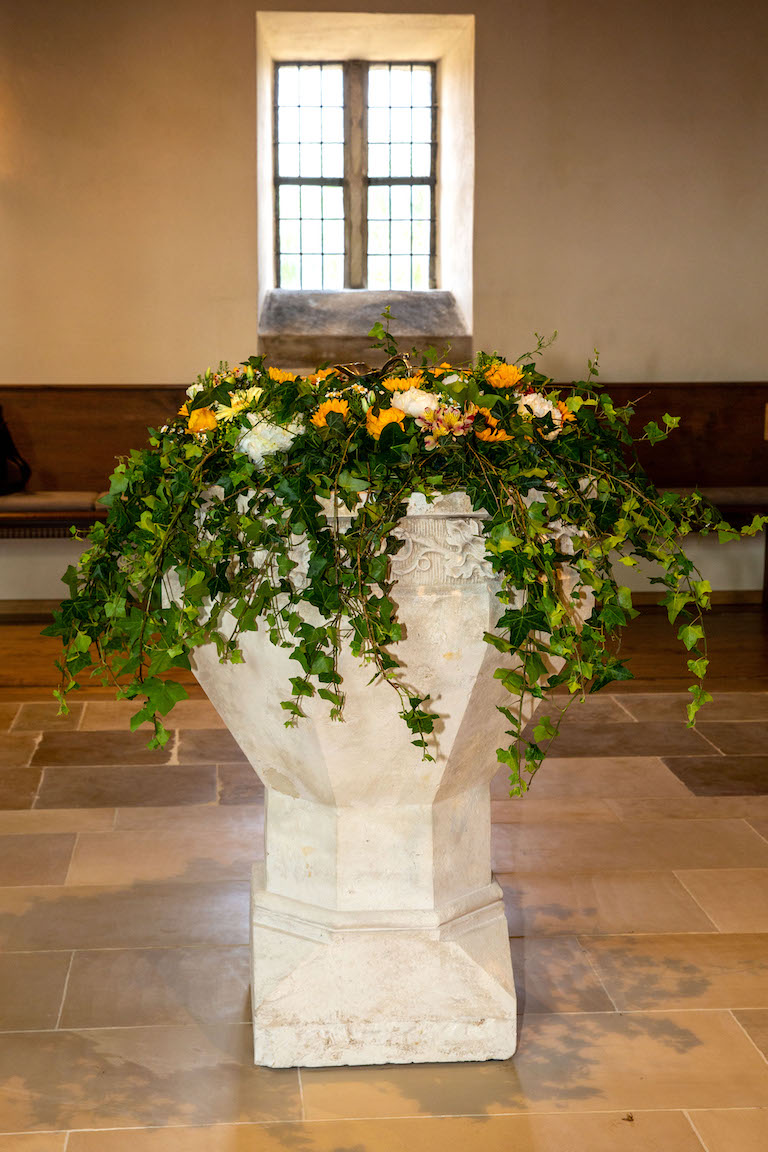 Taufstein geschmückt mit Blumen