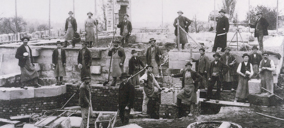 Schwarz-Weiss-Bild von Bauarbeitern auf der Kirchenbaustelle um 1900